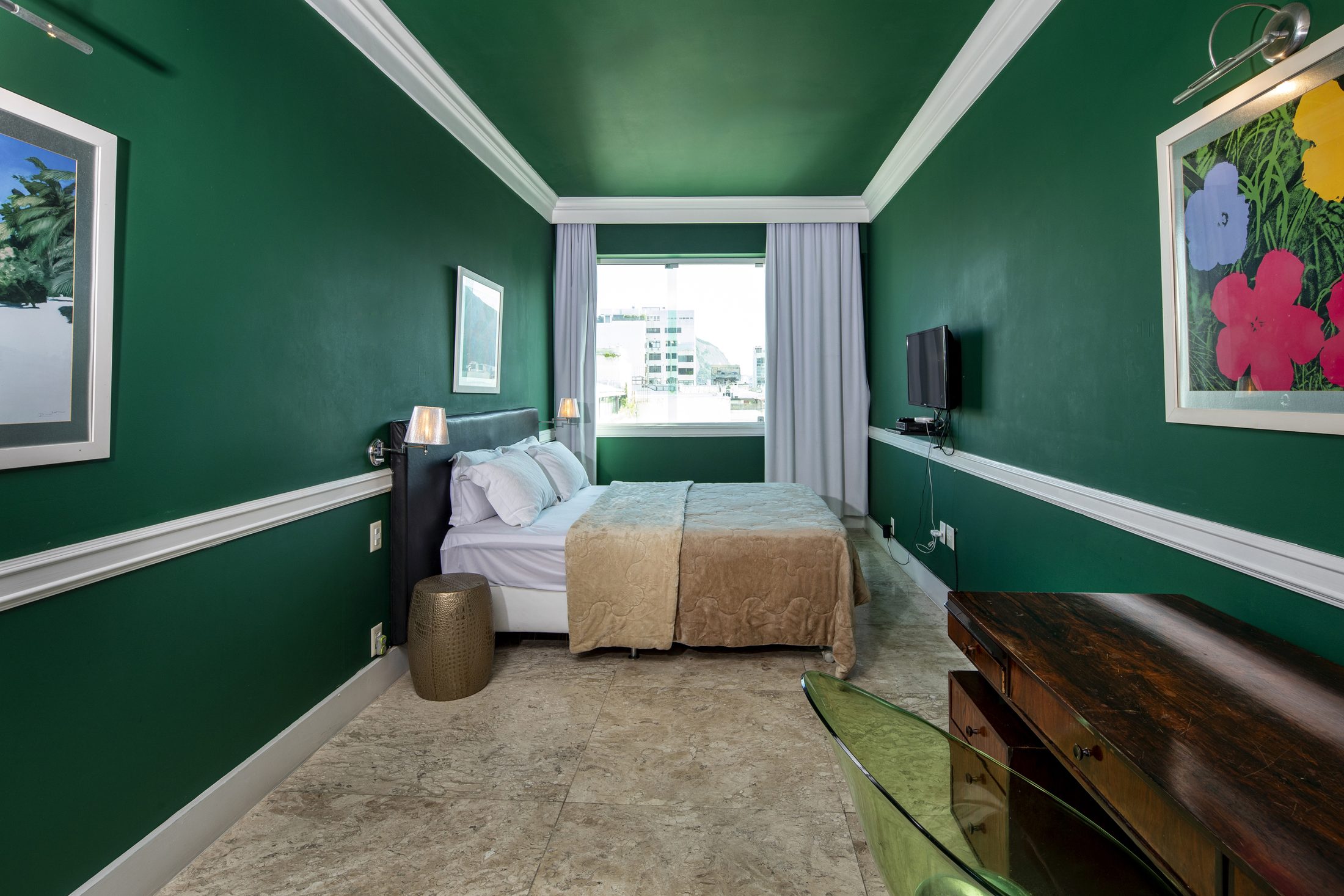 A suite with deep green walls, pop-art flowers and a sea-view window